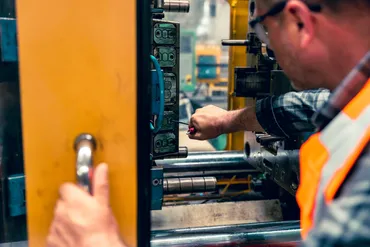 Technician operating industrial injection molding machine — Baked Industries